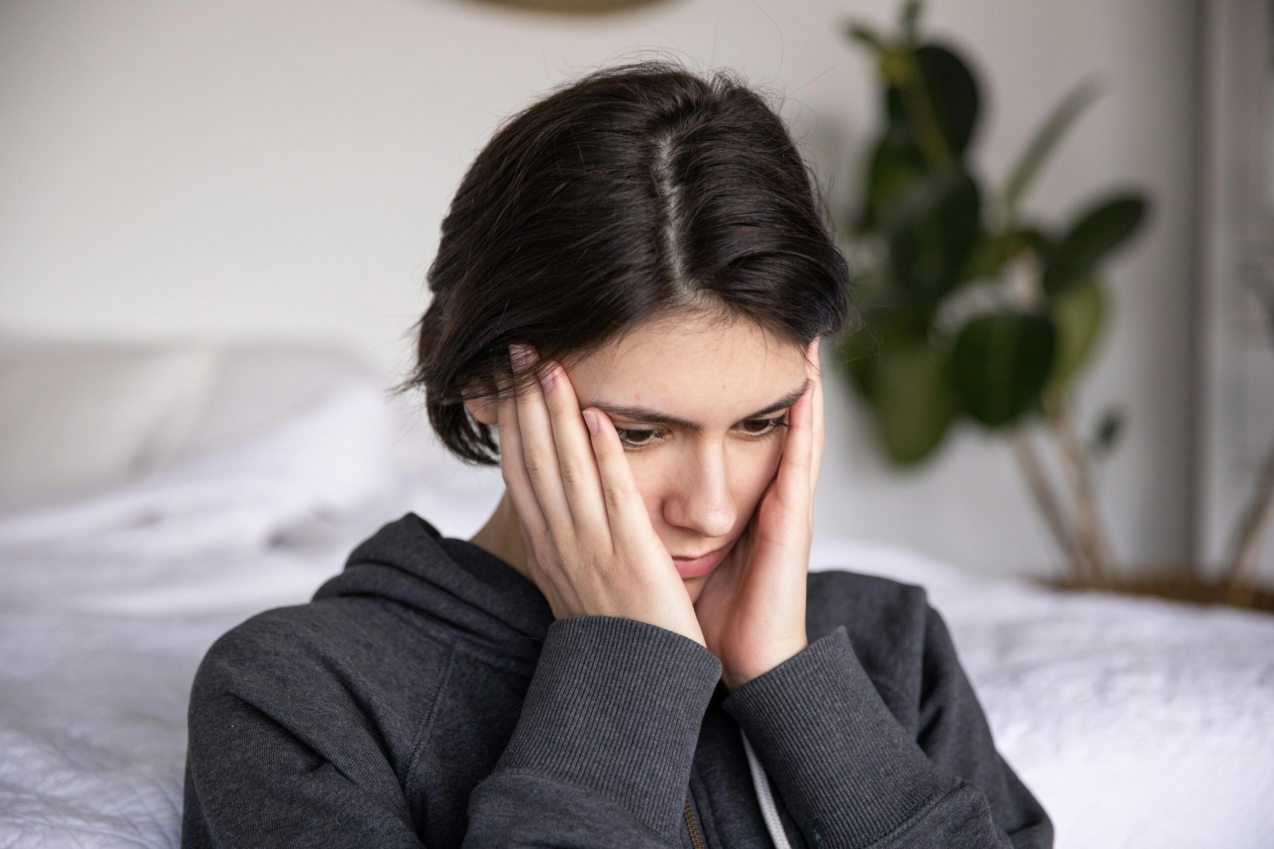 a woman in grey upper holding her head in her hands and thinking which driving school to choose